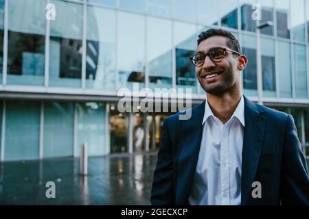Porträt eines jungen erfolgreichen Geschäftsmannes, der lächelnd vor dem Bankbüro steht Stockfoto