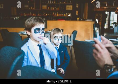 Sotschi Russland 31. Oktober 2020. Vater macht Fotos von Kindern am Telefon. Make-up auf einer Feier von Halloween. Stockfoto