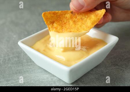 Weibliche Hand Dips Chip in Käsesauce, Nahaufnahme Stockfoto