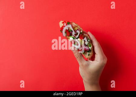 Weibliche Hand hält Bruschetta auf rotem Hintergrund Stockfoto