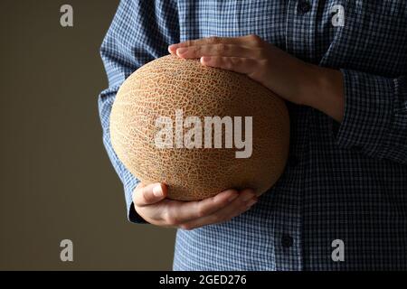 Frau im Hemd hält Korb mit Melone Stockfoto