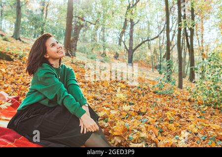 Porträt einer jungen lächelnden Frau im gelben Herbstpark. Fallende Blätter Stockfoto