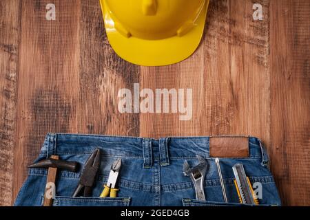 Draufsicht Designkonzept des Labor Day mit Arbeitswerkzeugen und Jeans auf Holztischhintergrund. Stockfoto