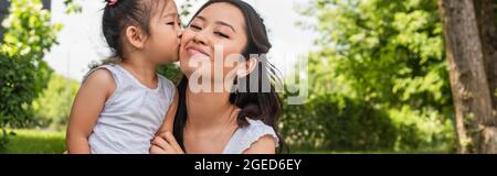 asiatische Kleinkind Mädchen küssen Wange der glücklichen Mutter im Park, Banner Stockfoto