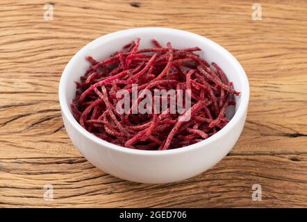 Rote Beete Streifen, im Julienne-Stil in einer Schüssel über einem Holztisch. Stockfoto