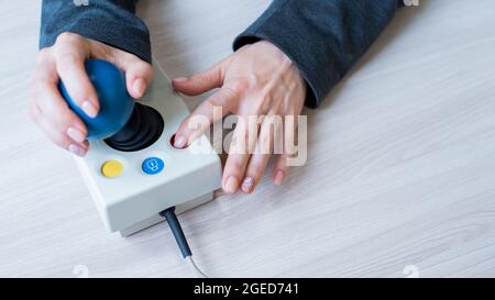 Frau mit zerebraler Lähmung arbeitet an einer spezialisierten Computermaus. Stockfoto