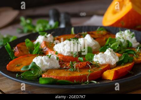 Vegetarisches Gericht mit rotiertem Kürbis, Ziegenkäse und grünem Salat Stockfoto