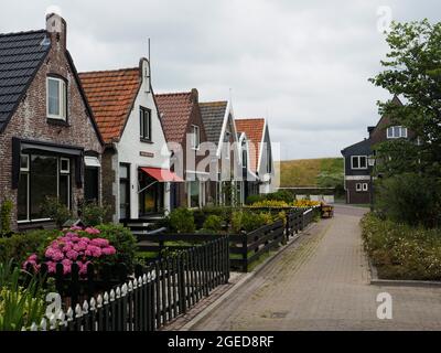 Kleine traditionelle alte holländische Häuser hinter dem Deich in Oudeschild auf der Insel Texel, Niederlande Stockfoto