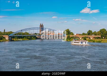 Blick über den alten Dom, die Sternenbrücke in der historischen Innenstadt von Magdeburg mit einem großen Touristenboot, das an der Elbe, Deutschland, bei Blue Sum, vorbei kommt Stockfoto