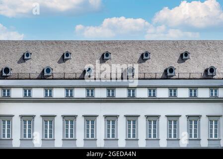 Das große Dach ist mit den flachen Fliesen des alten Hauses mit zwei runden Fenstern im Dachgeschoss und normalen Fenstern an der Wand bedeckt. Stockfoto