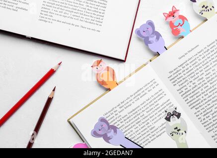 Niedliche Lesezeichen mit Büchern und Bleistiften auf weißem Hintergrund Stockfoto
