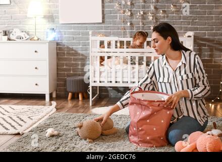 Mutter, die zu Hause Spielzeug in die Tasche legt Stockfoto