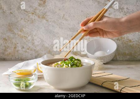 Frau, die leckere chinesische Suppe mit Huhn auf hellem Hintergrund isst, Nahaufnahme Stockfoto