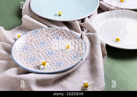 Schöne Teller mit Kamillenblumen auf farbigem Holzhintergrund Stockfoto