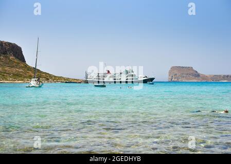 Herrlicher sonniger Tag in Balos, Griechenland mit Booten, die auf dem kristallblauen Wasser unter klarem Himmel segeln Stockfoto