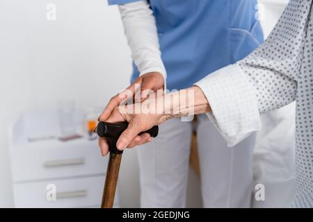 Beschnittene Ansicht einer afroamerikanischen Krankenschwester und eines älteren Patienten mit Gehstock Stockfoto