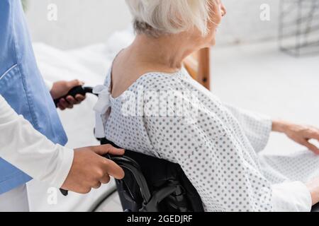 Abgeschnittene Ansicht einer afroamerikanischen Krankenschwester, die in der Nähe eines älteren Patienten im Rollstuhl steht Stockfoto