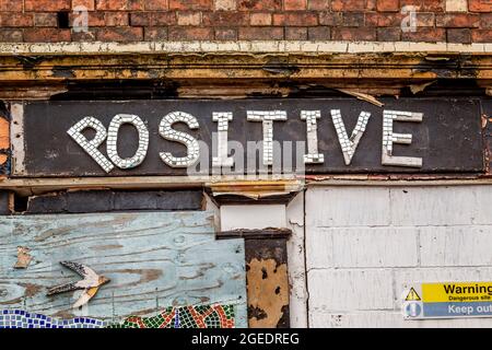 Eine aufgetaufte Ladenfront zeigt ironischerweise das Wort positiv auf der Beschilderung. Stockfoto
