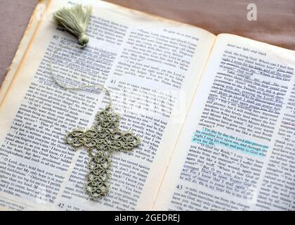 Handgehäkelte Lesezeichen liegen auf der geöffneten Bibel. Unterstrich Passagen zeigen Ermutigung und Trost. Stockfoto