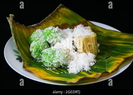 Drei Marktsnacks aus Indonesien, nämlich Klepon, getuk lindri und Wajik auf einem Teller mit einem Bananenblatt und bestreut mit geriebener Kokosnuss. Stockfoto