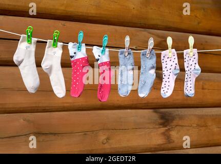 Kindersocken hängen an einer Wäscheleine. Socken in verschiedenen Farben hängen an einem Seil, das mit Wäscheklammer gepfropft ist. Stockfoto