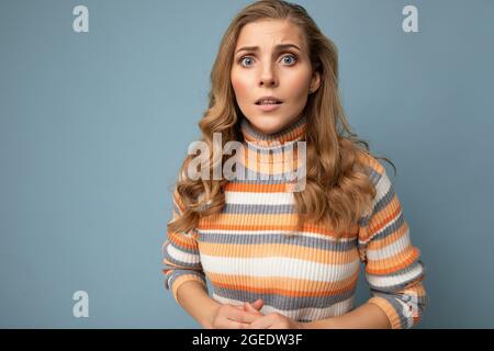 Foto-Porträt von jungen attraktiven schönen traurig aufgeregt nervös blonde Frau mit aufrichtigen Emotionen tragen gestreiften Pullover isoliert auf blauem Hintergrund Stockfoto