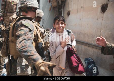 Ein Junge wird während einer Evakuierung am Hamid Karzai International Airport, Kabul, Afghanistan, am 18. August durch einen Evakuierungskontrollpunkt (ECC) verarbeitet. Die US-Marineinfanteristen unterstützen das Außenministerium bei der geordneten Entsendung von designiertem Personal in Afghanistan. (USA Marine Corps Foto von Staff Sgt. Victor Mancilla) Stockfoto