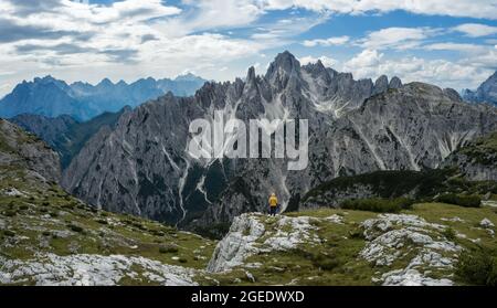 Mann Wanderer stehen und bewundern atemberaubende Schönheit der beeindruckenden zerklüfteten Gipfel der Cadini di misurina Berggruppe in den Dolomiten, Italien, Teil der Tre Cime Stockfoto