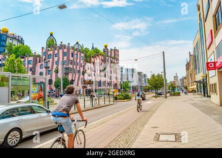 Hundertwasser Grüne Zitadelle im historischen Zentrum und Einkaufsviertel Magdeburgs am sommerblauen Himmel mit vorbeifahrenden Radfahrern, Magdebb Stockfoto