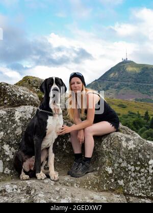 Eine Wandererin mit ihrem Hund mit einer wunderschönen Aussicht auf einen vulkanischen Berg. Vulkan Puy de Dome in der Auvergne. Stockfoto