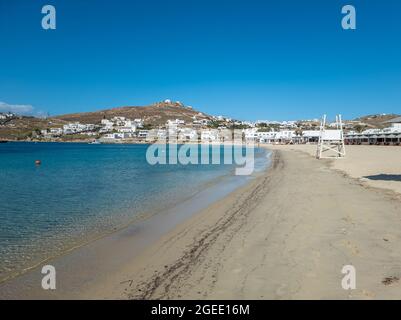 Ornos leerer tropischer Sandstrand Rettungsschwimmer Turm transparentes ruhiges Meer klarer blauer Himmel weiß getünchte Gebäude Werbung für Mykonos Insel, Kykladen Stockfoto