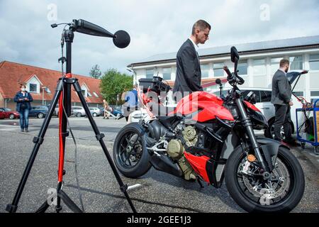 Harrislee, Deutschland. August 2021. Auf dem Gelände des neuen Prüflabors des Kraftverkehrsamtes (KBA) in Harrislee steht neben einem Motorrad und verschiedenen Mikrofonen ein Mitarbeiter des Kraftverkehrsbundesamtes zur Lautheitsmessung. Quelle: Gregor Fischer/dpa/Alamy Live News Stockfoto