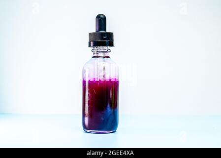 Glasflasche mit violetter Farbe auf weißem Hintergrund Stockfoto