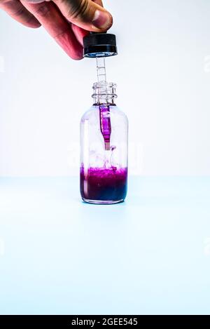 Glasflasche mit violetter Farbe auf weißem Hintergrund Stockfoto