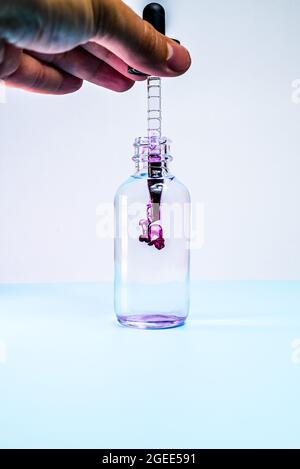 Glasflasche mit violetter Farbe auf weißem Hintergrund Stockfoto