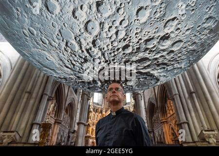 London, Großbritannien. 19. August 2021. Vicar James Heard posiert mit Luke Jerram ‘Museum of the Moon, einem Kunstwerk mit einem Durchmesser von 7 Metern, das detaillierte NASA-Aufnahmen der Mondoberfläche zeigt. Im Maßstab 1:500,000 stellt jeder Zentimeter der intern beleuchteten Kugel 5 km der Mondoberfläche dar. Das Touring-Kunstwerk ist bis zum 30. August in der St. John the Baptist Church in der Nähe von Shepherd’s Bush zu sehen und ist Teil des diesjährigen Kensington and Chelsea Festivals. Kredit: Stephen Chung / Alamy Live Nachrichten Stockfoto