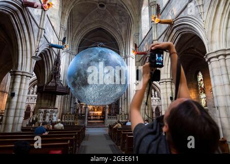 London, Großbritannien. 19. August 2021. Ein Besucher blickt auf Luke Jerram ‘Museum of the Moon, ein Kunstwerk mit einem Durchmesser von 7 Metern, das detaillierte NASA-Aufnahmen der Mondoberfläche zeigt. Im Maßstab 1:500,000 stellt jeder Zentimeter der intern beleuchteten Kugel 5 km der Mondoberfläche dar. Das Touring-Kunstwerk ist bis zum 30. August in der St. John the Baptist Church in der Nähe von Shepherd’s Bush zu sehen und ist Teil des diesjährigen Kensington and Chelsea Festivals. Kredit: Stephen Chung / Alamy Live Nachrichten Stockfoto