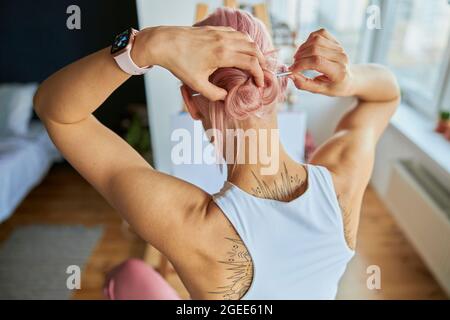 Eine Künstlerin macht auf einem hellen Balkon mit einem Pinsel in der Nähe einer Staffelei ein Brötchen Stockfoto