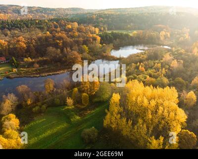 Vögel Auge Ansicht von Wald und einem kleinen See. Antenne bunten Wald Szene im Herbst mit orange und gelb Laub. Herbst Landschaft in der Nähe von Vilnius, Li Stockfoto