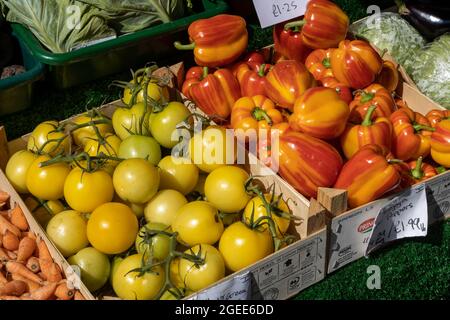 Gelbe Tomaten und rot-gelb gestreifte Paprika in Holzkisten Stockfoto