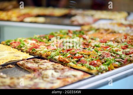 Quadratische Stücke von Pizza auf der Theke der kleinen italienischen Pizzeria in Bergamo Stadt, Italien angezeigt. Stockfoto