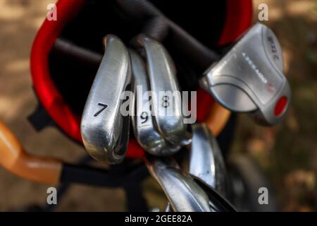 Minsk. Weißrussland - 25.07.2021 - Golfschläger in einer roten Tasche Nahaufnahme grünen Rasen Hintergrund Stockfoto