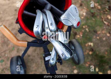 Minsk. Weißrussland - 25.07.2021 - Golfschläger in einer roten Tasche Nahaufnahme grünen Rasen Hintergrund Stockfoto