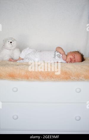 Kleines Baby in Weiß schläft mit einem weißen Teddy Stockfoto