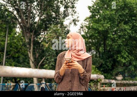 Stock Foto der schönen muslimischen Frau zu Fuß und suchen ihr Handy Stockfoto