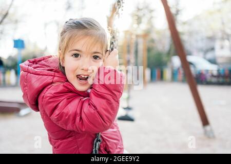 Ein schulpflichtig lächelndes Mädchen, das auf der Fahrt fröhlich lächelt Schaukeln im Park Stockfoto