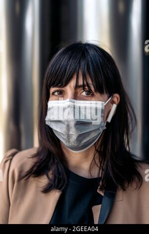 kaukasische Geschäftsfrau mit Gesichtsmaske und Kopfhörern Stockfoto