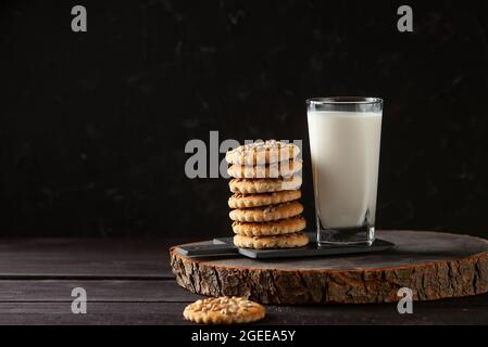 Frische gesunde Milch und hausgemachte Kekse auf dunklem Holztisch Stockfoto