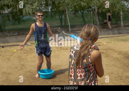 Odesa rgn., Ukraine, 06. August 2021: Ein Mädchen schießt in einem Sommerlager auf einen Mann mit einer Wasserpistole Stockfoto