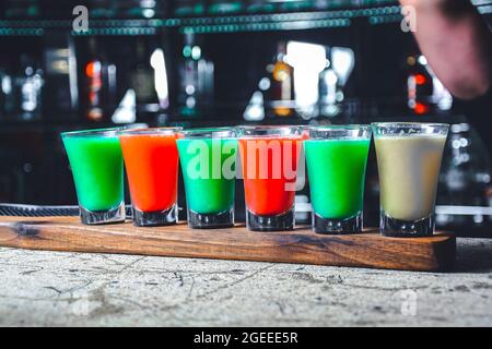 Der Barkeeper bereitet Cocktails zu. Mehrfarbiger Cocktail. Erfrischende Cocktails. regenbogen-Cocktails. regenbogen-Cocktail in Vintage-Gläsern. Cocktails gibt es Stockfoto